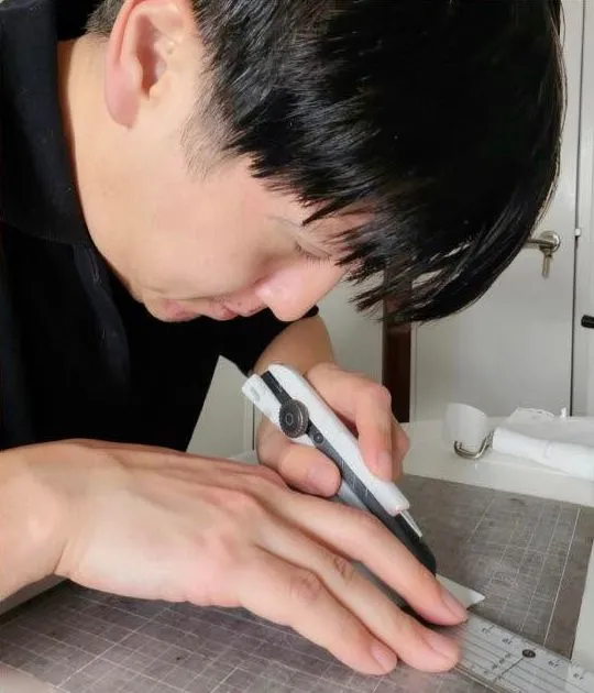 定規とカッティングマットの上で道具を手にする人物